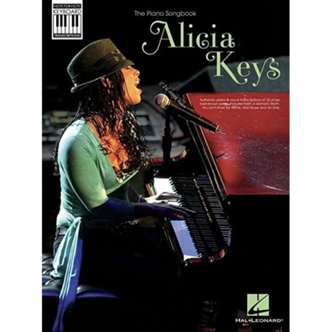 Alicia Keys singing and playing piano wearing a hat and a green shirt